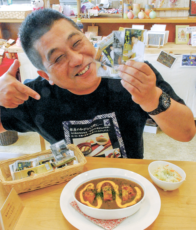 ブロマイドを手に、コラボカレーをPRする野々村代表