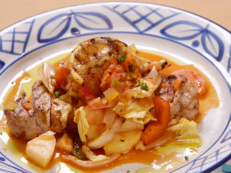 はっしーが注文したのはこちら！網目の焼き色も美しいポークソテーに、たっぷりの野菜のソースがかけられています。一緒に焼いたレモンをトッピングして爽やかに
