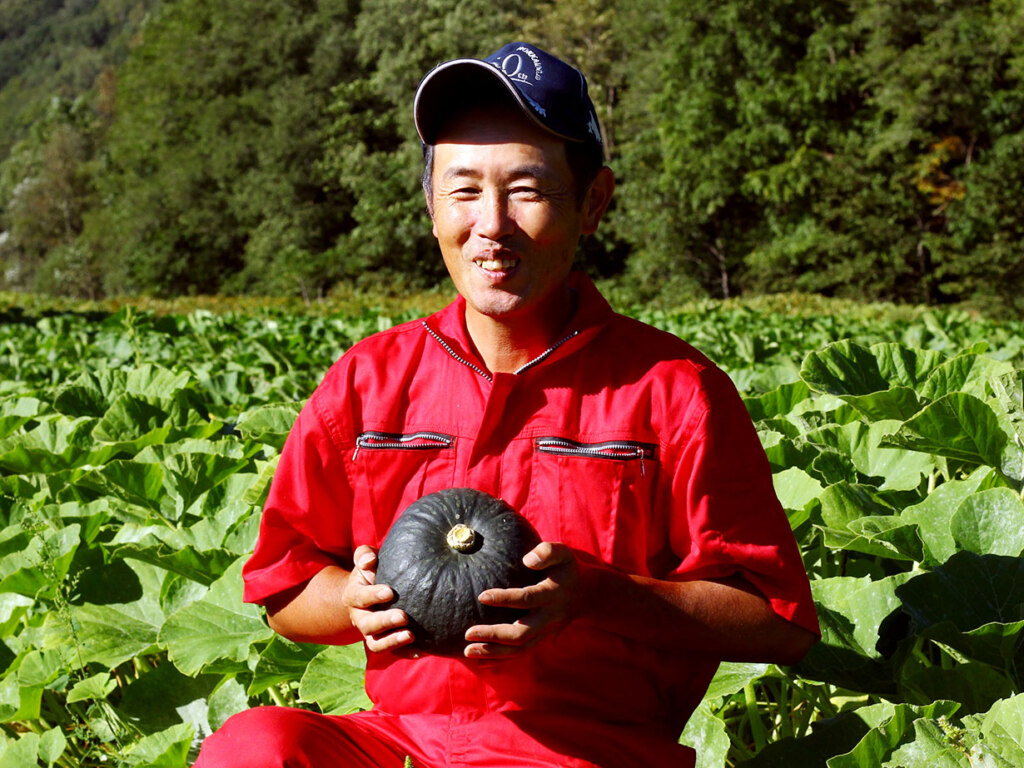 南瓜生産部会長を務める竹本さん。手をかけ育てた「くり大将」を手に少し安堵の表情。収穫後、しっかりと熟成させたのちに出荷します